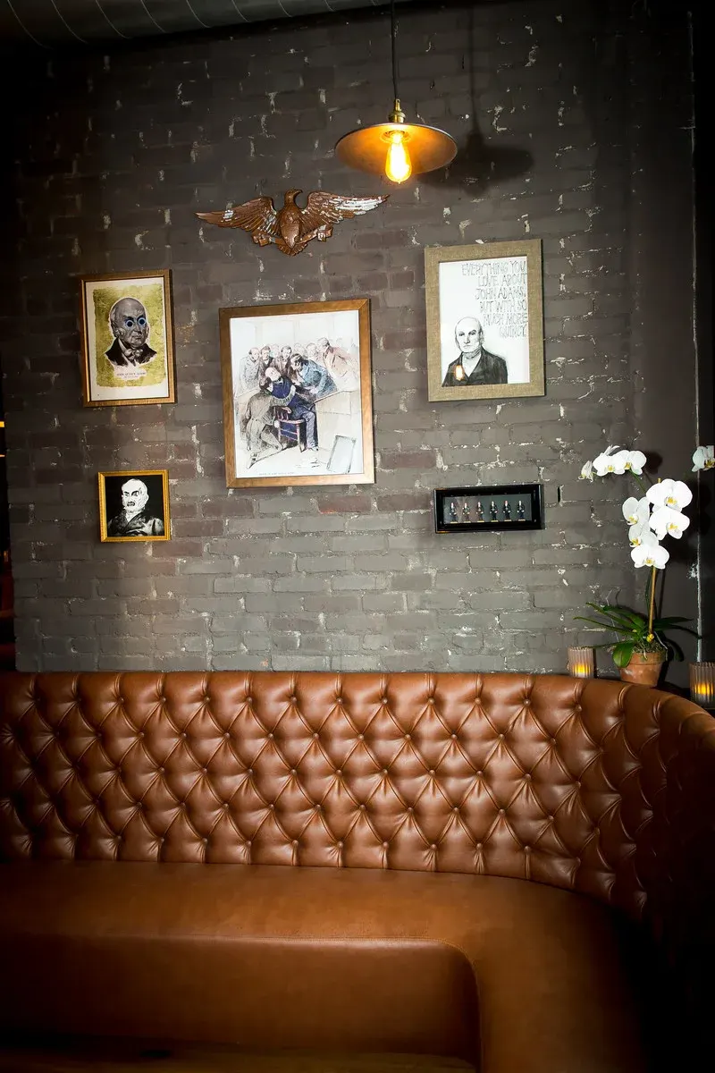 Framed portraits above a leather banquette