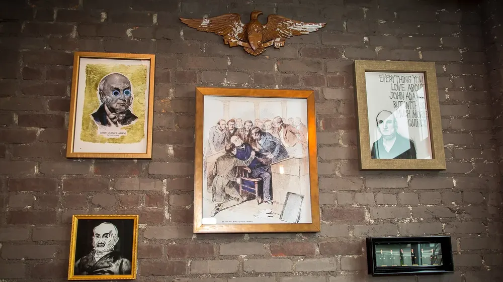 Framed historic portraits on the brick wall inside the tavern